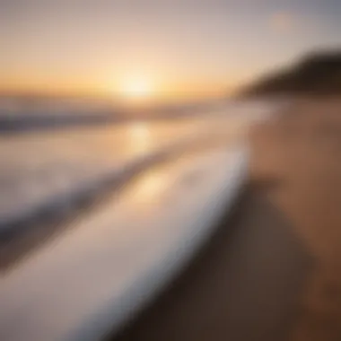 Surfboard resting on the beach with the sun peeking over the horizon