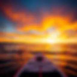 A vibrant sunset reflecting on calm waters with an inflatable paddle board in the foreground.