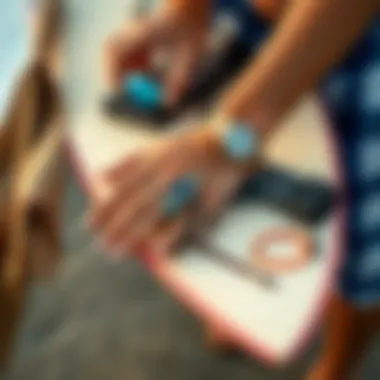 Hand arranging surfer bracelets alongside surfboard and beach accessories