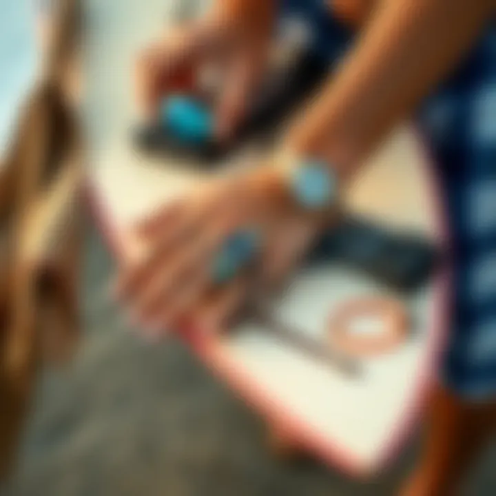 Hand arranging surfer bracelets alongside surfboard and beach accessories